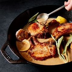 a skillet filled with meat and vegetables on top of a black counter next to a person holding a spoon