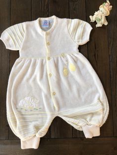 This adorable unisex romper is in excellent condition and appears to have never been worn. It is super soft to the touch and has an appliqué of little bears in white with embroidered yellow hearts and green and yellow and white checked balloons.  The roads company was started in the 60s in Venezuela and is still in operation. I am not able to precisely date this piece but according to the rodesbaby.com website they were in full manufacturing capacity by the 70s.  Size: 6 months  Materials: 100% acrylic Can be machine washed in cold water Cute Cream Onesie For Loungewear, Cream Short Sleeve Bubble Romper For Summer, Cream Cotton Bubble Romper With Short Sleeves, Cute Yellow Onesie For Loungewear, Yellow Short Sleeve Onesie For Spring, Spring Yellow Short Sleeve Onesie, Cute Cream Cotton Onesie, Cute Cream Onesie For Spring, Spring Baptism Cotton Onesie