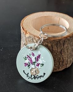 a keychain with the word bloom on it sitting next to a piece of wood