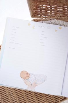 an open baby's book sitting on top of a wicker basket