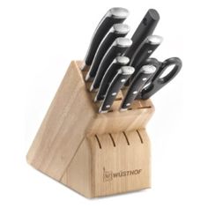 a set of knives sitting on top of a wooden block in front of a white background