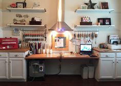 a desk with a computer on top of it in a room filled with shelves and other items