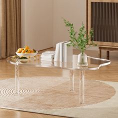 a glass table sitting on top of a wooden floor next to a vase filled with oranges