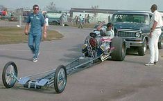 two men standing next to a drag car