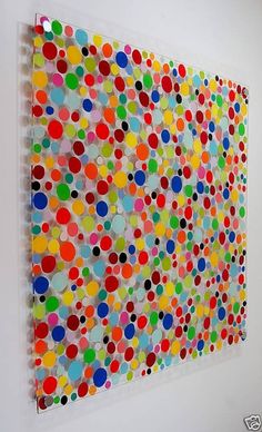 an art piece is hanging on the wall with colorful circles painted on it's surface