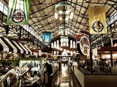 the inside of a store with lots of flags hanging from the ceiling and people shopping