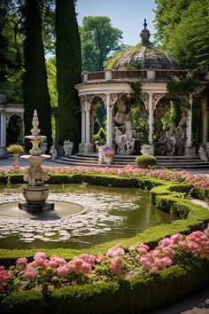 a fountain in the middle of a garden surrounded by trees and bushes with pink flowers around it