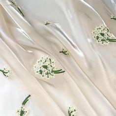 white fabric with small flowers and green stems on it's side, as seen from above