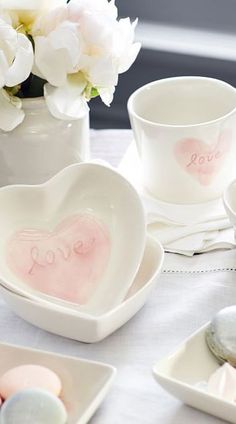 the table is set with dishes, cups and spoons that have hearts painted on them