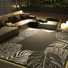 a living room area with couches, rugs and lights on the floor at night