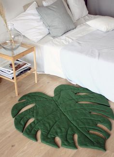 a bedroom with a bed and a green rug on the floor in front of it