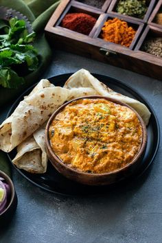 a black plate topped with food next to tortilla chips and other foodstuffs