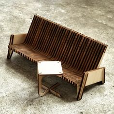 a wooden bench sitting on top of a cement floor next to a small white table