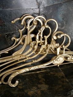 an ornate gold metal bench sitting on top of a black tile floor next to a wall