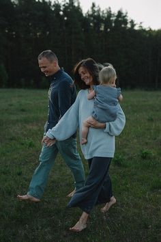 a man, woman and child are walking in the grass with their arms around each other