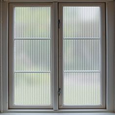 an open window with vertical blinds on the outside and inside windows that are closed to let in light