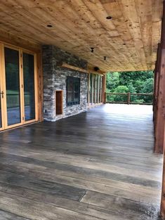 an empty covered porch with sliding glass doors and stone fireplace in the center, surrounded by wood paneling