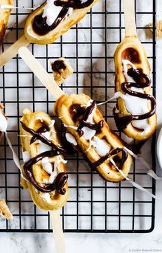 chocolate covered pretzels are sitting on a cooling rack with toothpicks in them