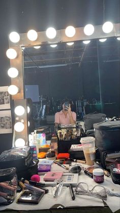 a woman taking a selfie in front of a vanity mirror with makeup and accessories on it