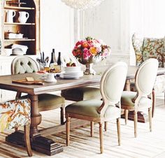 a dining room table with several chairs around it and a chandelier hanging from the ceiling