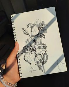 a hand holding a notebook with flowers drawn on it