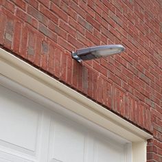 a street light attached to the side of a brick building next to a white garage door