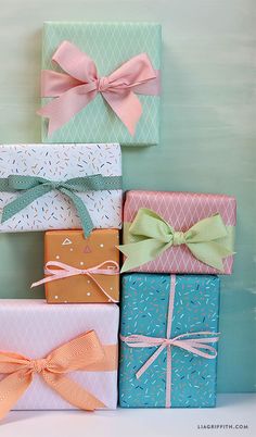 several wrapped presents are stacked on top of each other in different colors and patterns with bows