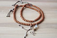 this is real sandall wood mala with fine quality beads 8mm mix with mala counter and om charms 108 beads 18inch long necklace Handmade Wooden Beaded Bracelets For Meditation, Spiritual Wooden Beaded Bracelets, Holistic Brown Mala With Wooden Beads, Brown Wooden Beads Spiritual Mala, Spiritual Brown Wooden Beads Mala, Brown Wooden Beads Mala As Gift, Buddhist Mala, Om Charm, 108 Mala Beads