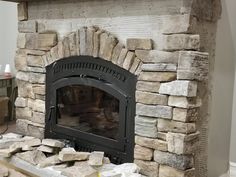 a stone fireplace in a living room next to a fire place with logs on the floor