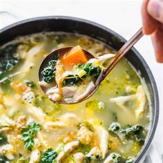 a spoon full of soup with broccoli, chicken and carrots in it