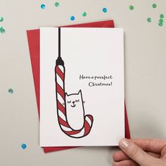 a hand holding a christmas card with a cat in the hat hanging from a red and white striped umbrella