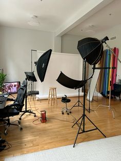 several photography equipment are arranged on the floor in front of a white wall and wooden floors