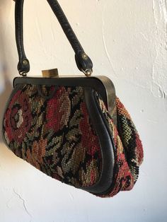 "1950s classic carpet bag structured bag originally designed for the classic woman with a boho soul. Vintage fall leaves and floral with black needlepoint carpet bag with leather strap and edging. Brass metal clasp and hardware has an authentic patina. Black fabric lining with a single zippered security pocket. Unmarked Size: 7\" tall x 12.5\" wide x 4.5\" deep at base. Handle is a total of 12\" for about a 5\" -6\" drop. Condition: Vintage excellent with obvious patina. Inside there is a very s Vintage Shoulder Bag For Daily Use In Fall, Vintage Brown Satchel For Fall, Vintage Brown Bag For Fall, Vintage Tote Shoulder Bag For Fall, Vintage Rectangular Bags For Vintage Events, Vintage Evening Bag In Tapestry Material, Vintage Rectangular Bags For Events, Vintage Rectangular Bags For Fall, Vintage Tapestry Bag For Evening