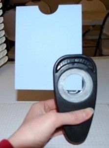 a hand holding a remote control in front of a stack of white cards on a table