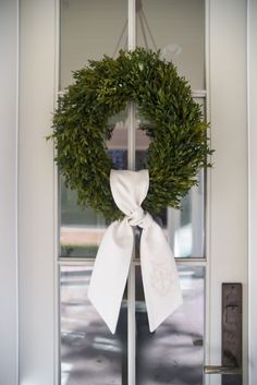 a wreath with a white bow hangs on the front door