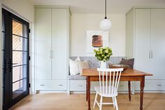 a dining room table with white chairs in front of it and built - in cupboards