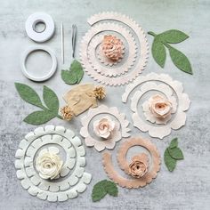 paper flowers are laid out on a table with scissors and other crafting supplies around them