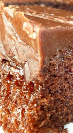 a piece of chocolate cake sitting on top of a white plate covered in frosting