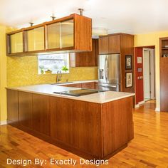 a kitchen with yellow walls and wooden floors, an island in the middle is surrounded by cabinets