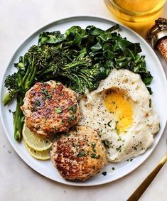 a white plate topped with meat patties, mashed potatoes and broccoli