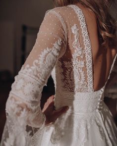 the back of a woman's wedding dress with sheer sleeves and beaded details