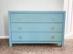 a blue chest of drawers in a room with carpeted flooring and white walls