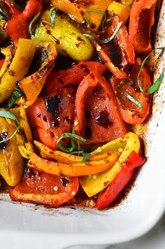 a white casserole dish filled with roasted peppers and other veggie ingredients