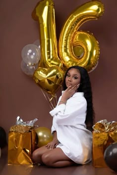 a woman sitting in front of balloons and presents