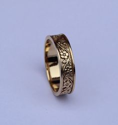 a gold wedding ring with an intricate design on the outside and inside, against a blue background