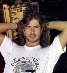 a man with long hair standing on top of a building next to a cityscape