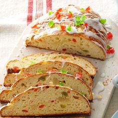 a loaf of bread with white icing and colorful toppings on it sitting on a cutting board