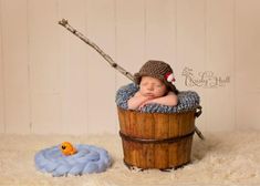 a baby sleeping in a bucket with a stick