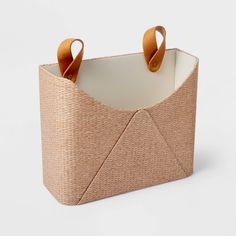 a woven basket with two handles on the front and one handle at the back, sitting on a white surface