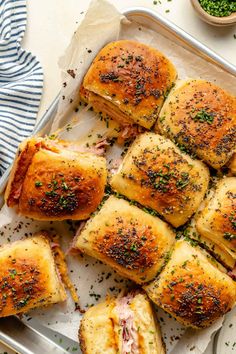 several pieces of bread with meat and herbs on them in a baking pan next to some seasoning